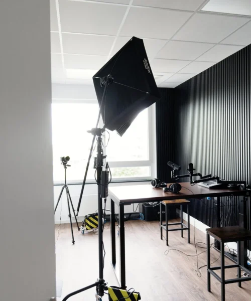 Studio photography setup with a large black softbox light, tripods, and cables in a bright office space